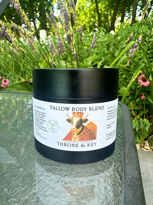 Tallow body blend jar with 'Throne & Key' branding on a glass surface with a garden background.